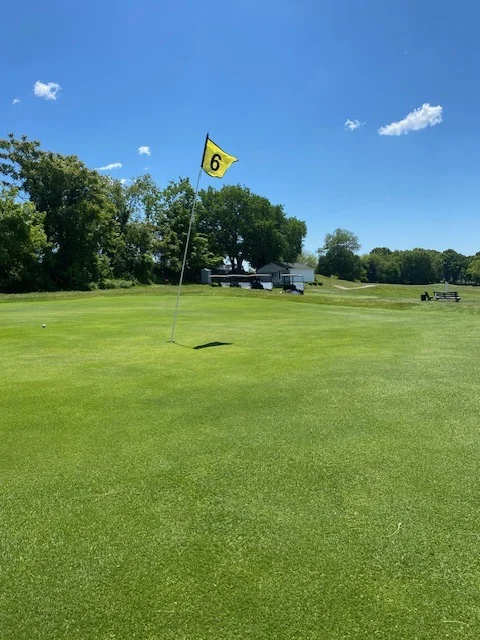 Hole 6 pin flag on a green with the clubhouse visible in the distance at Silver Spring Golf Club Riverside RI