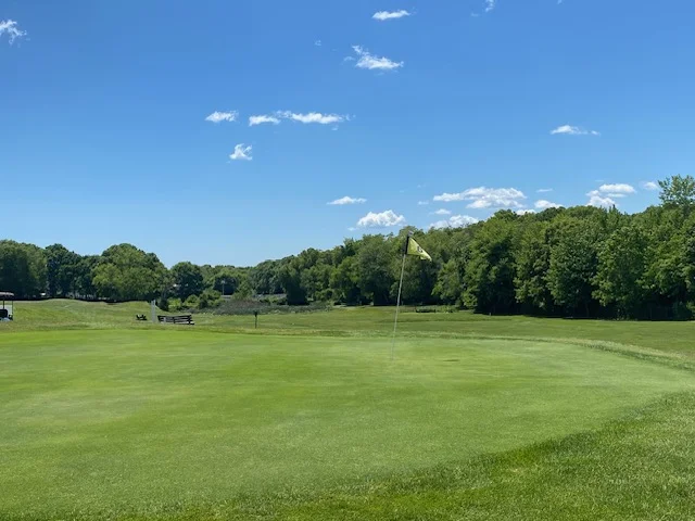 Wide green beneath soft summer clouds at Silver Spring Golf Course in Riverside RI